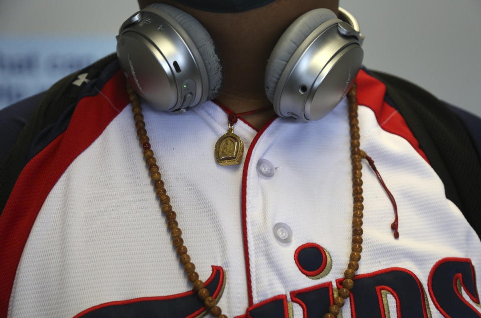 Jalue Dorje wears headphones, a Minnesota Twins jersey, and Tibetan mala beads, which are used to count the repetition of prayers or mantras, as he waits to board a plane bound for New York at the Minneapolis−Saint Paul International Airport on Wednesday, July 21, 2021, in Minneapolis. (AP Photo/Jessie Wardarski)
