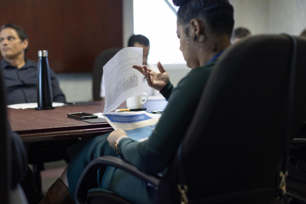 A person looks over papers while seated at a conference room table