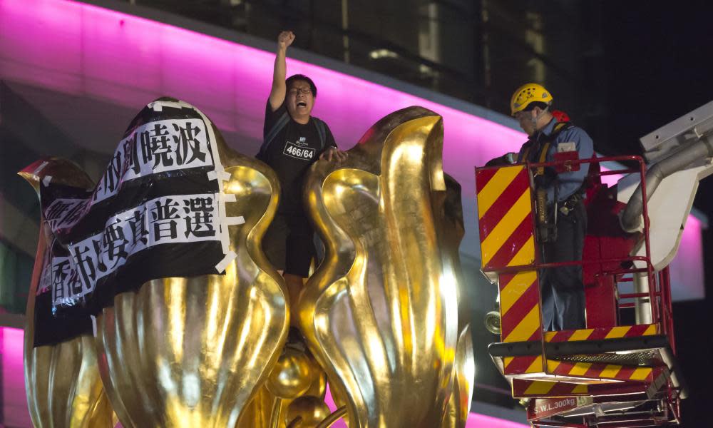 Authorities try to remove a pro-democracy activist in Hong Kong who on Wednesday hung a banner that reads ‘Release Liu Xiaobo unconditionally, Hong Kong people want genuine universal suffrage’.