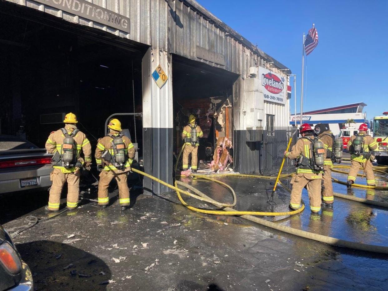 Firefighters work at the scene of a fire at Loveland's Automotive Service Inc. on Palmdale Road in Victorville on Friday, Jan. 21, 2022.