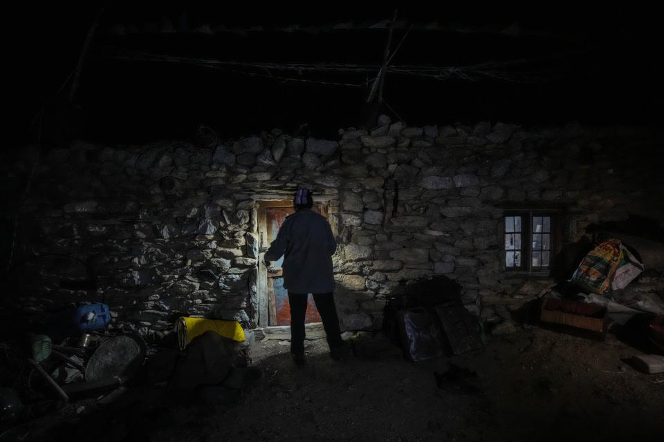 A nomad enters his mud house as he uses a torch on a dark autumn night in the remote Kharnak village in the cold desert region of Ladakh, India, Saturday, Sept. 17, 2022. The region's sparsely populated villages have witnessed shifting weather patterns that have already altered people's lives through floods, landslides and droughts. (AP Photo/Mukhtar Khan)