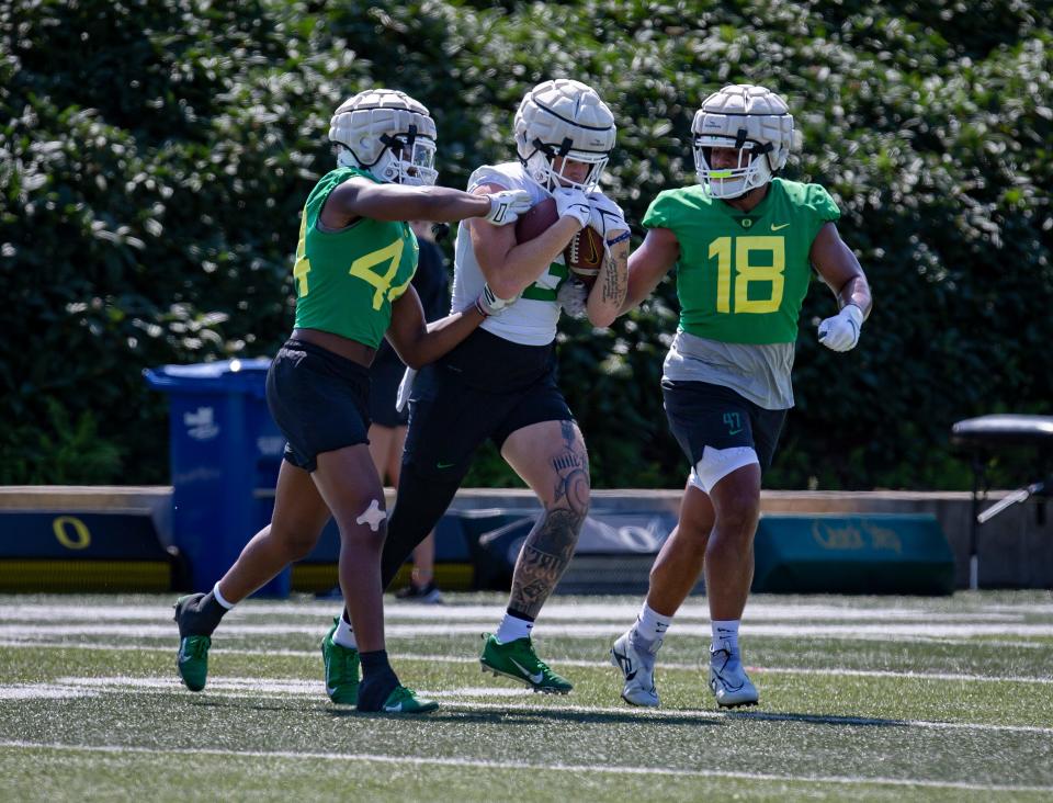 Oregon tight end Terrance Ferguson attempts to control a pair of footballs during a drill at practice Friday, Aug. 19, 2022, in Eugene, Ore. 