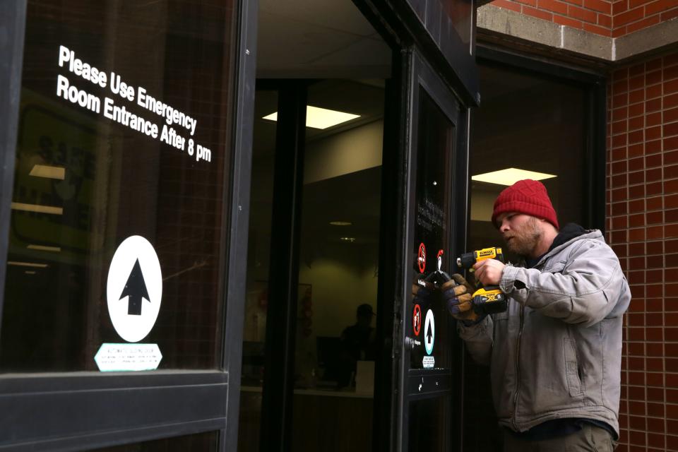 A Latitude Signage & Design employee works to replace the vinyl door markers at the main entrance of Iowa Health Care’s downtown campus Wednesday, Jan. 31, 2024 in Iowa City, Iowa.