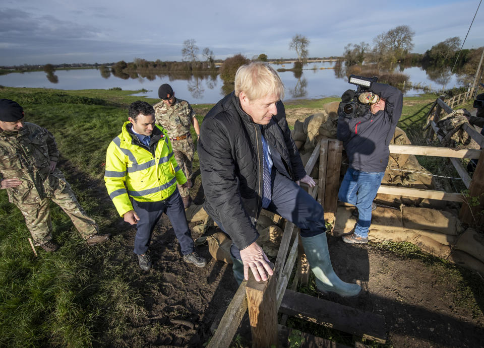 Britain's Prime Minister Boris Johnson, clambers over a fence, during a visit to see the effects of recent flooding, in Stainforth, England, Wednesday, Nov. 13, 2019. (Danny Lawson/Pool Photo via AP)