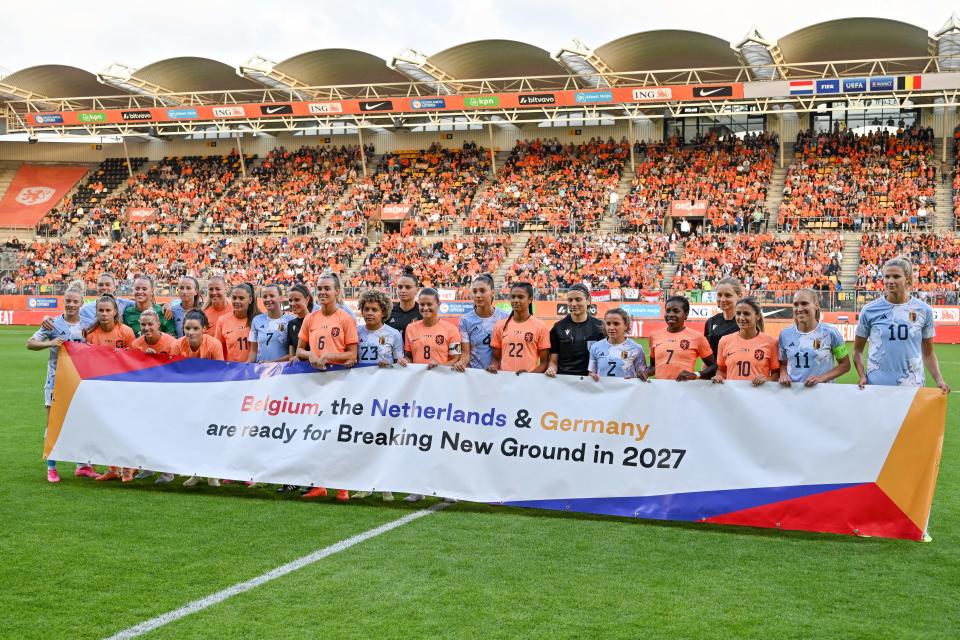 Jugadoras holandesas y belgas se reúnen detrás de una pancarta para apoyar la candidatura del BND para la Copa Mundial Femenina de la FIFA 2027 antes de un partido amistoso de fútbol el 2 de julio en Kerkrade.  (Foto de David Cutry/Belga Mag/AFP vía Getty Images)