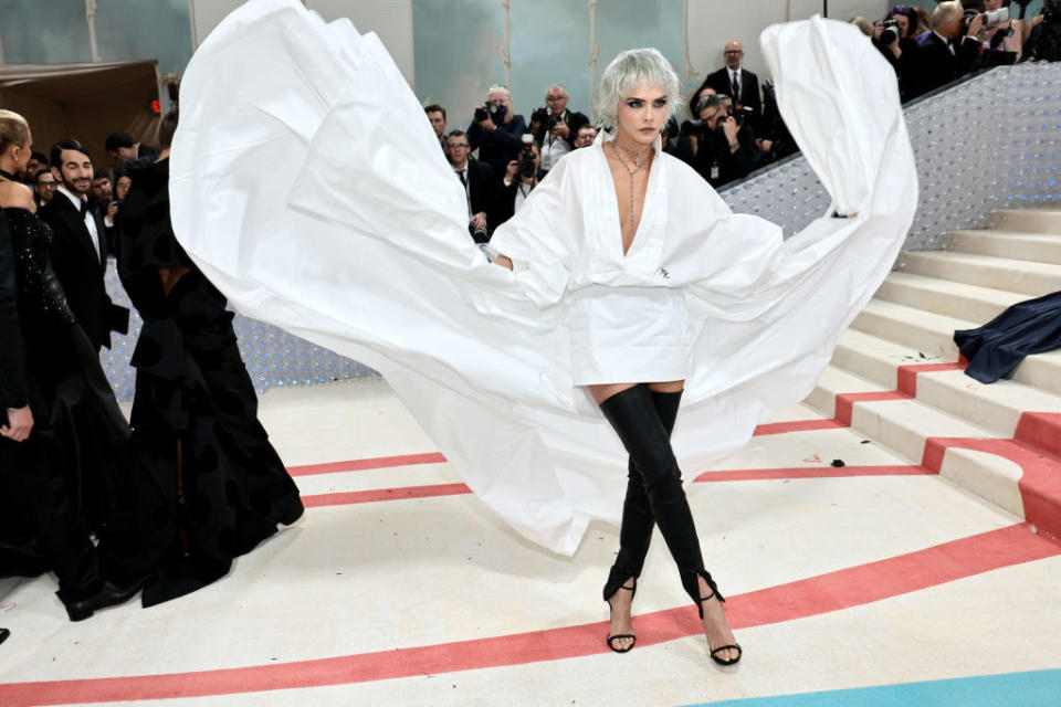 Cara Delevingne attends The 2023 Met Gala in black leggings and a white flowing shirt