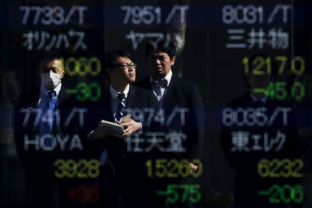 People are reflected in a display showing market indices outside a brokerage in Tokyo, Japan, February 10, 2016. REUTERS/Thomas Peter