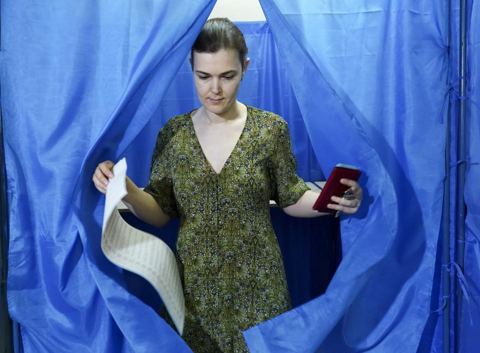 A woman leaves a booth at a polling station during at a parliamentary election in Kiev, Ukraine, Sunday, July 21, 2019. The party of new President Volodymyr Zelenskiy is widely predicted to get the largest share of votes in Sunday's election. (AP Photo/Evgeniy Maloletka)