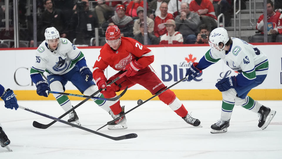 Vancouver Canucks right wing Ilya Mikheyev (65) and Vancouver Canucks defenseman Quinn Hughes (43) defend Detroit Red Wings left wing Lucas Raymond (23) in the third period of an NHL hockey game Saturday, Feb. 10, 2024, in Detroit. (AP Photo/Paul Sancya)