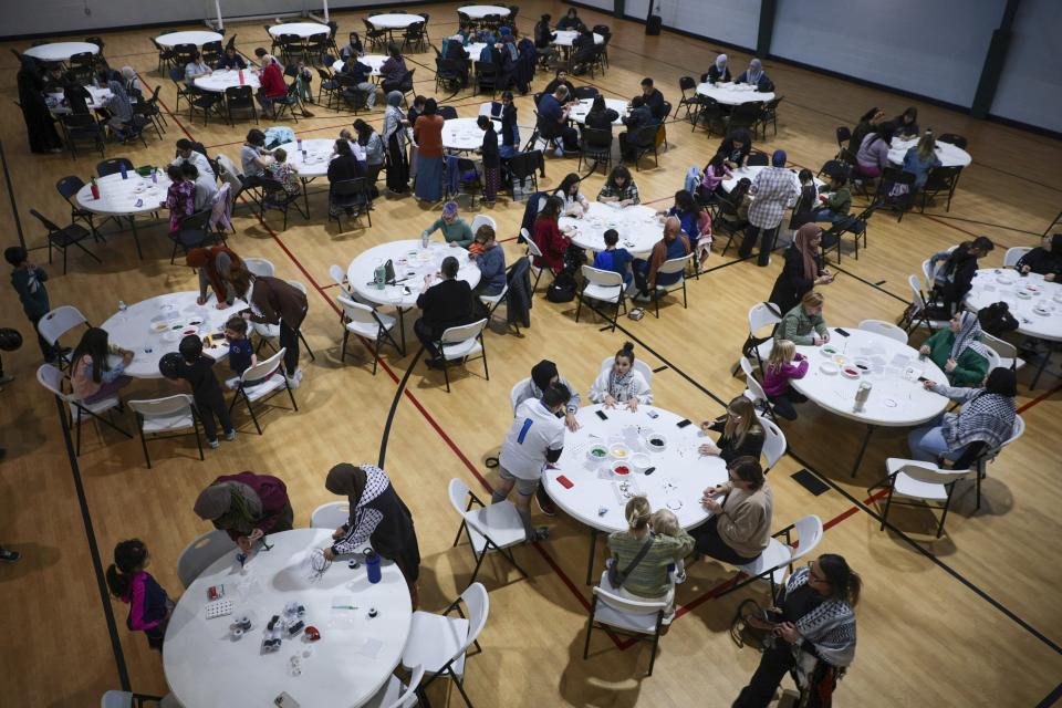 People gather to make bracelets with former Girl Scout Troop 149 as they fundraise for children affected by the war in Gaza at the Dar Al Jalal Masjid Mosque in Hazelwood, Mo. on Saturday, March 2, 2024. The girls' goal is to make 2000 bracelets. (Vanessa Abbitt/St. Louis Post-Dispatch via AP)