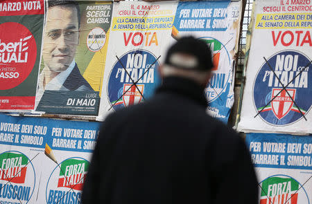 A man stands to look electoral posters in Pomigliano D'Arco, near Naples, Italy, February 21, 2018. Picture taken February 21, 2018. REUTERS/Alessandro Bianchi