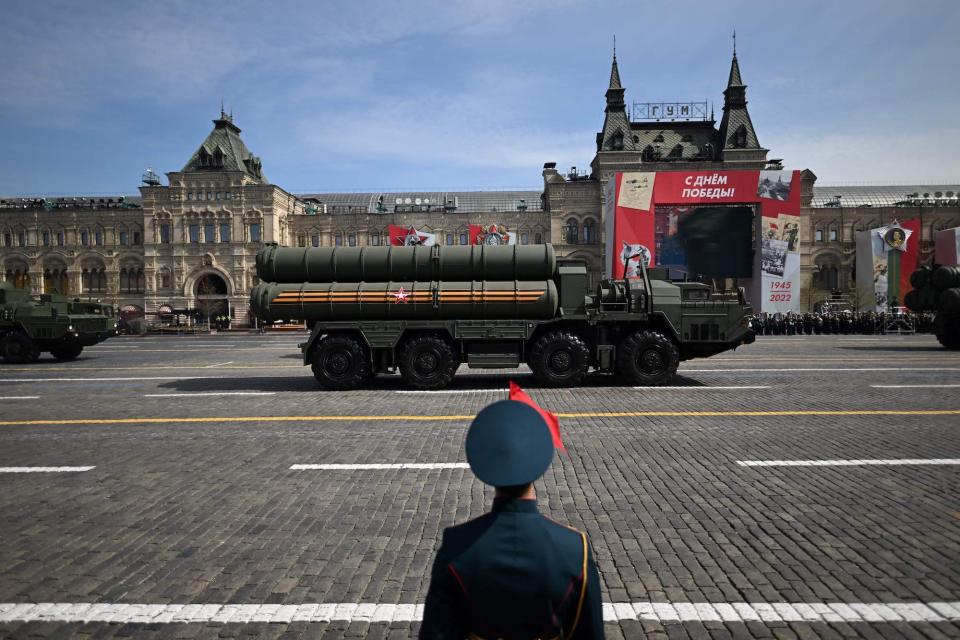 A Russian S-400 missile air defence systems passes through Red Square with a figure wearing military dress in the foreground with their back to the camera