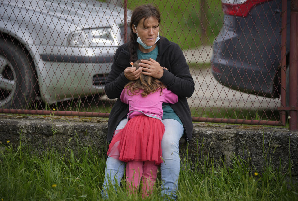 A woman comforts her daughter after she was slightly hit by a ball while playing during an eyesight examination performed by volunteer ophthalmologists, in Nucsoara, Romania, Saturday, May 29, 2021. (AP Photo/Vadim Ghirda)
