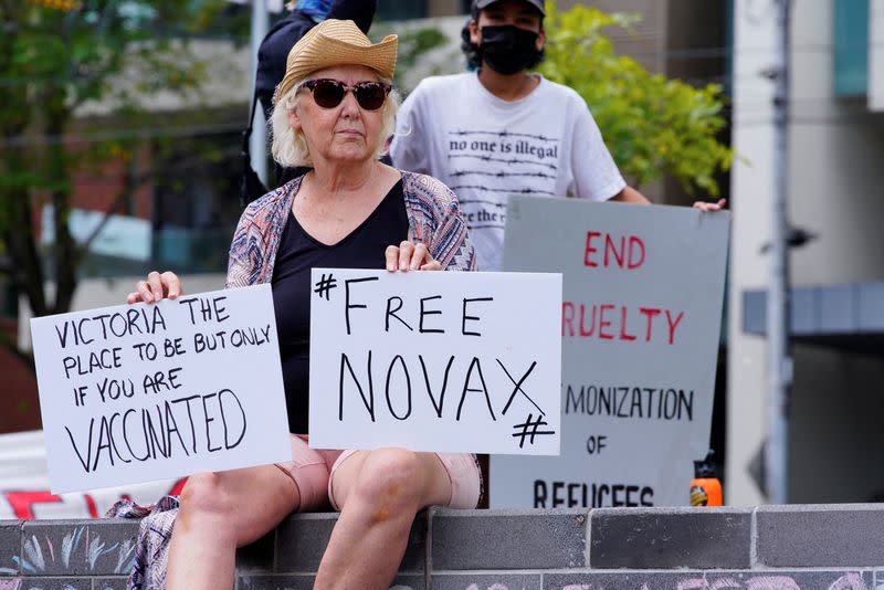 A protestor holds signs outside Park Hotel, where Serbian tennis player Novak Djokovic is believed to be living, in Melbourne