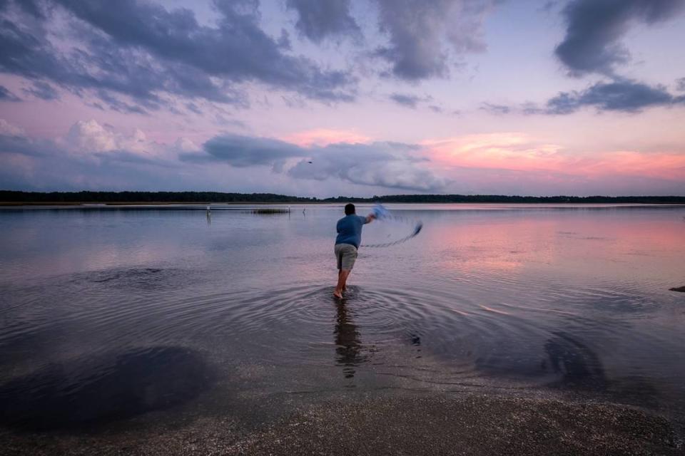 A fisherman casts his net from a shell island in Murrells Inlet, S.C. as the rising tide covers most of the shoreline. Oct. 16, 2020.