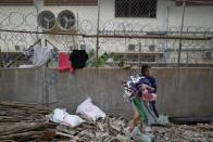 Una trabajadora recoge la ropa colgada en una valla, situada entre una fábrica y el edificio en el que viven los trabajadores en un barrio a las afueras de Phnom Penh, capital de Camboya. (Reuters/Damir Sagolj)