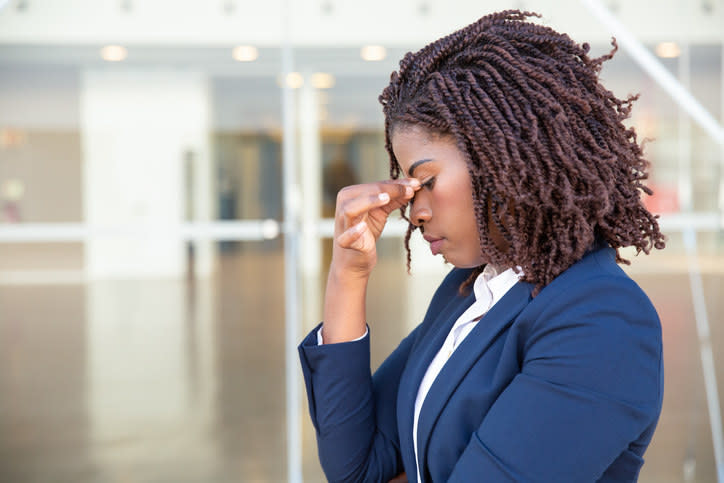 A woman in a business suit rubbing her upper nose.