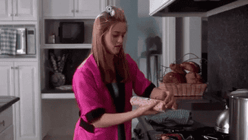 cher from "clueless" dropping something into the oven