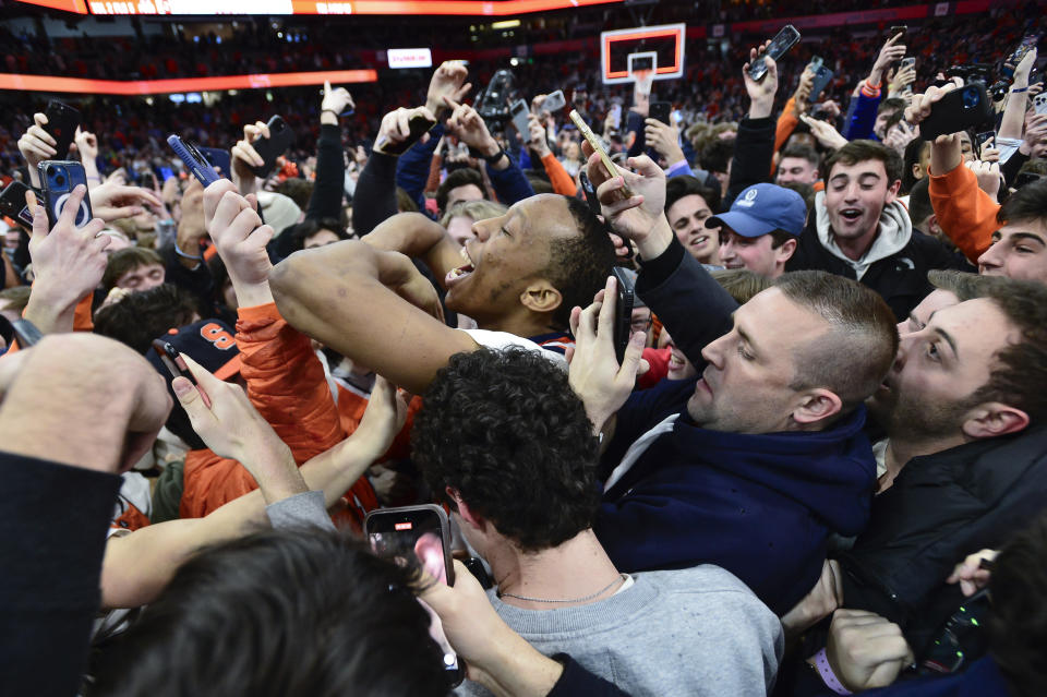 Syracuse guard Quadir Copeland, center, celebrates with fans that rushed the court after the team's win against North Carolina in an NCAA college basketball game in Syracuse, N.Y., Tuesday, Feb. 13, 2024. (AP Photo/Adrian Kraus)