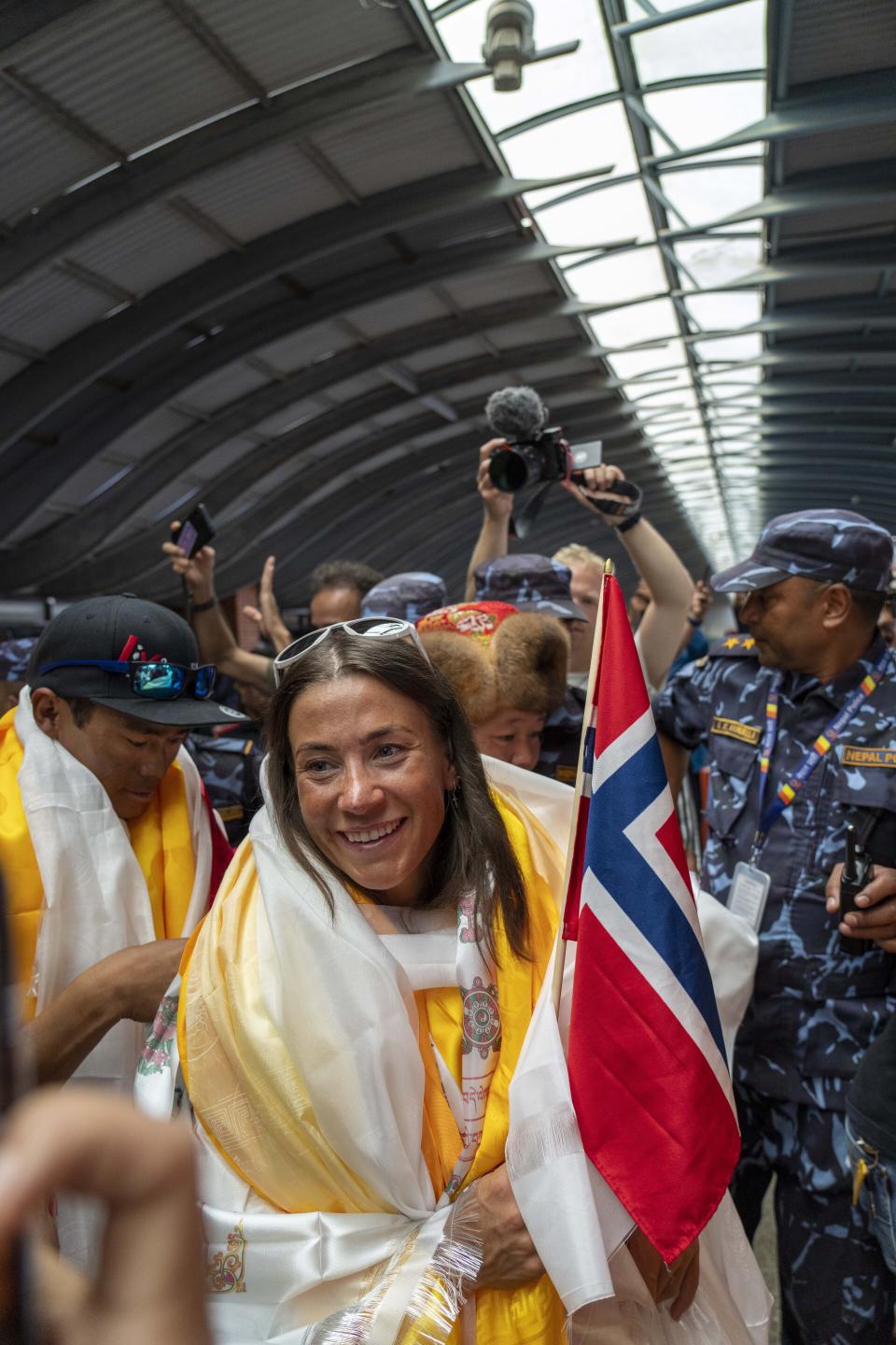 Norwegian woman mountain climber Kristin Harila, center who on Thursday set a new record by scaling the world's 14 highest peaks in 92 days smiles as she and her Nepali Sherpa guide Tenjen Sherpa, arrive at the airport in Kathmandu, Nepal, Saturday, Aug.5, 2023. (AP Photo/Niranjan Shreshta)