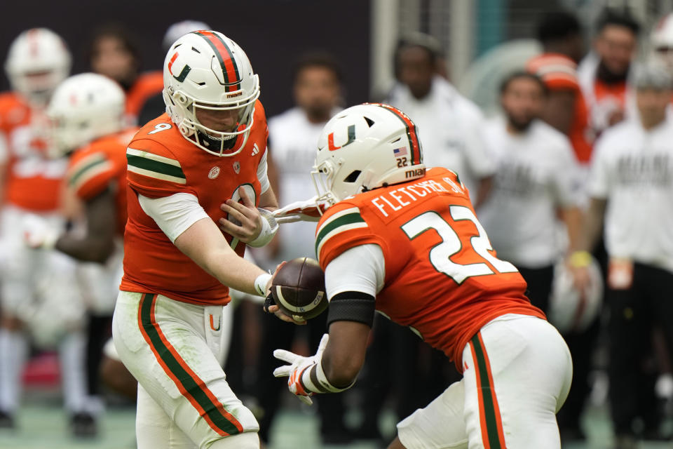 Miami quarterback Tyler Van Dyke (9) hands off to running back Mark Fletcher Jr. (22) during the first half of an NCAA college football game against Louisville, Saturday, Nov. 18, 2023, in Miami Gardens, Fla. (AP Photo/Wilfredo Lee)