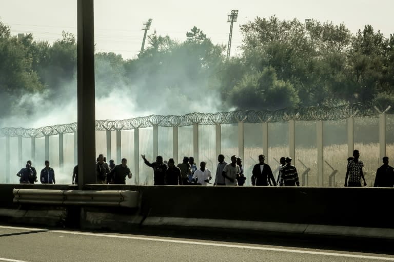 Migrants run away from tear gas during clashes with riot police trying to prevent them from getting into trucks heading to Great Britain, on September 21, 2016 in Calais