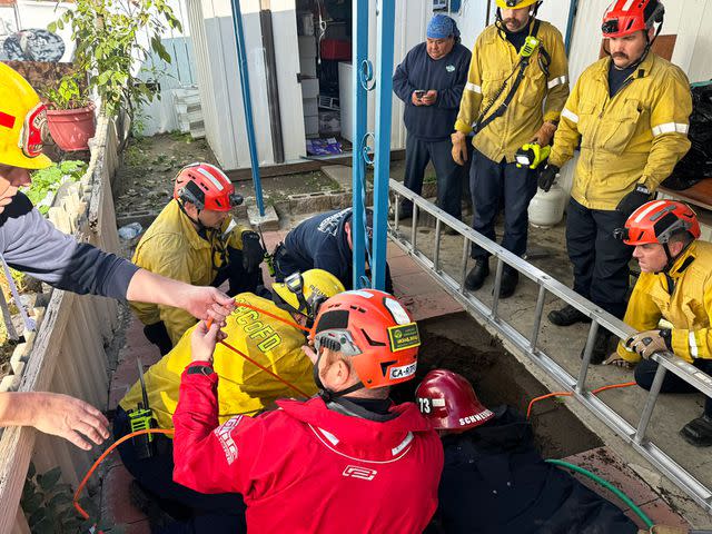 <p>San Bernardino County Fire/X</p> Rescuers work to saved a woman who fell into a 25-foot sinkhole in Fontana, Calif.