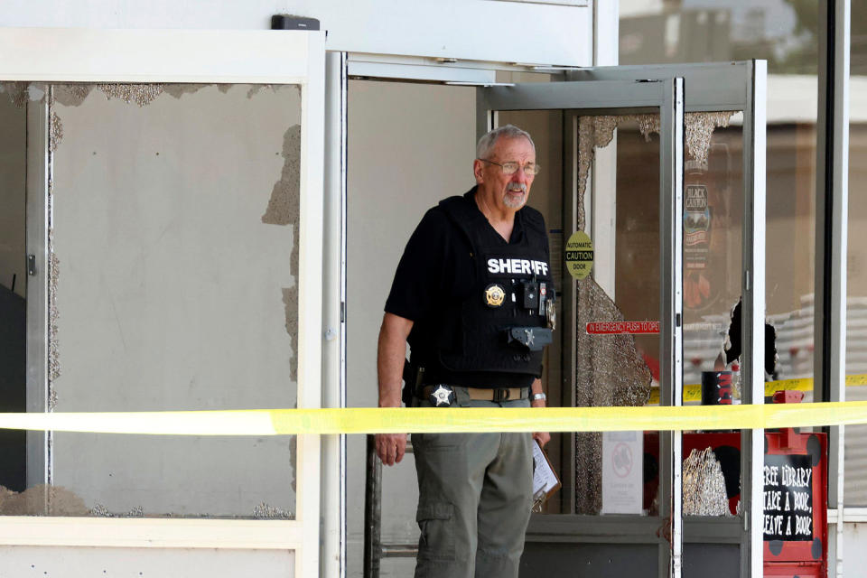 A law enforcement officer stands at the entrance to the store (Colin Murphey/Arkansas Democrat-Gazette via AP)