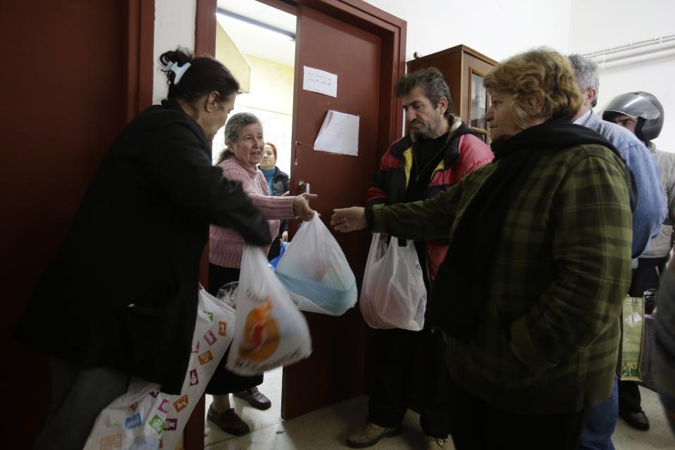 In this Wednesday, Feb. 12, 2014 photo unemployed people receive meals from social worker Athanasia Siampou, center, at Perama municipality, on the fringes of Athens' port of Piraeus. Perama’s unemployment is among the worst in Greece, where the nationwide figure for November was 28 percent, according to the statistical authority on Thursday, Feb. 13, 2014. (AP Photo/Thanassis Stavrakis)