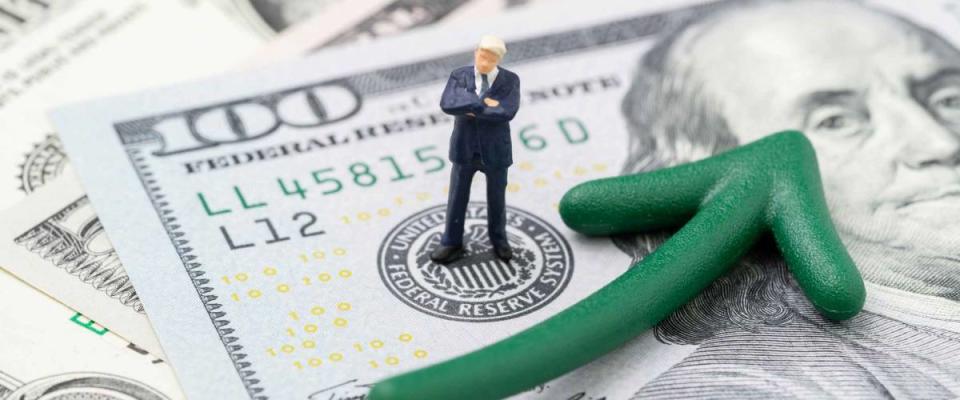 FED consider interest rate hike, world economics and inflation control, miniature businessman leader standing on US Federal Reserve emblem on dollars banknote with green arrow rising up.