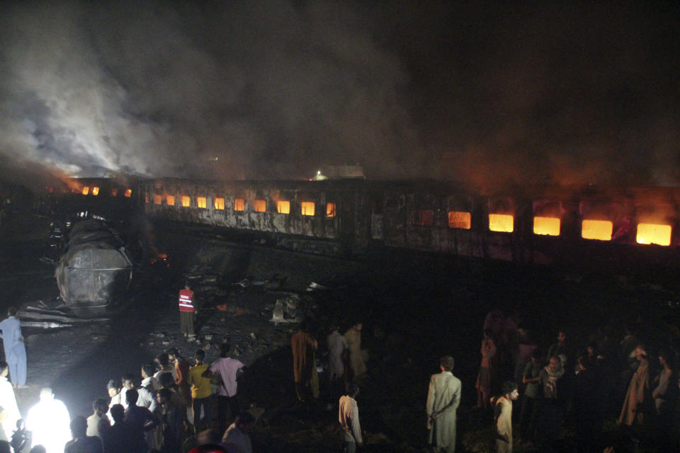 People look at a burning passenger train in Shaikhupura, near Lahore, Pakistan, early Tuesday, March 28, 2017. Authorities in Pakistan say a passenger train has collided with an oil tanker truck, killing at least one person and injuring others. (AP Photo/K.M. Chaudary)