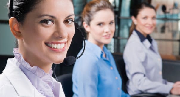 Portrait of a customer service representative smiling with her colleagues in the background