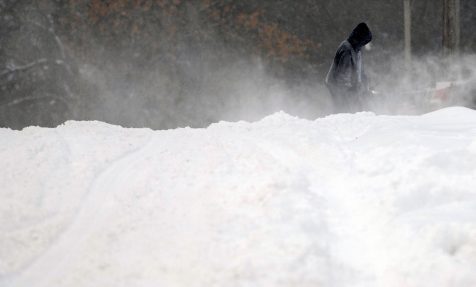 The wind whips the light snow as a Bismarck, N.D. homeowner clears the snow from a driveway with a snow blower, before the city snow plows made a pass through the neighborhood Thursday, Dec. 27, 2018. Forecasters posted a blizzard warning for parts of the Dakotas and Minnesota as a major winter storm delivered heavy snow and gusty winds to the region. (Mike McCleary/The Bismarck Tribune via AP)