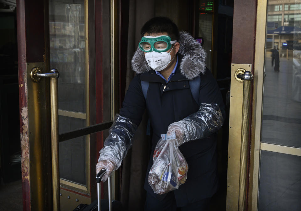 Un hombre chino usa una máscara protectora y gafas de natación después de bajarse de un tren cuando él y otros regresan de las vacaciones del Festival de Primavera el 31 de enero de 2020 en Beijing, China (Photo by Kevin Frayer/Getty Images).