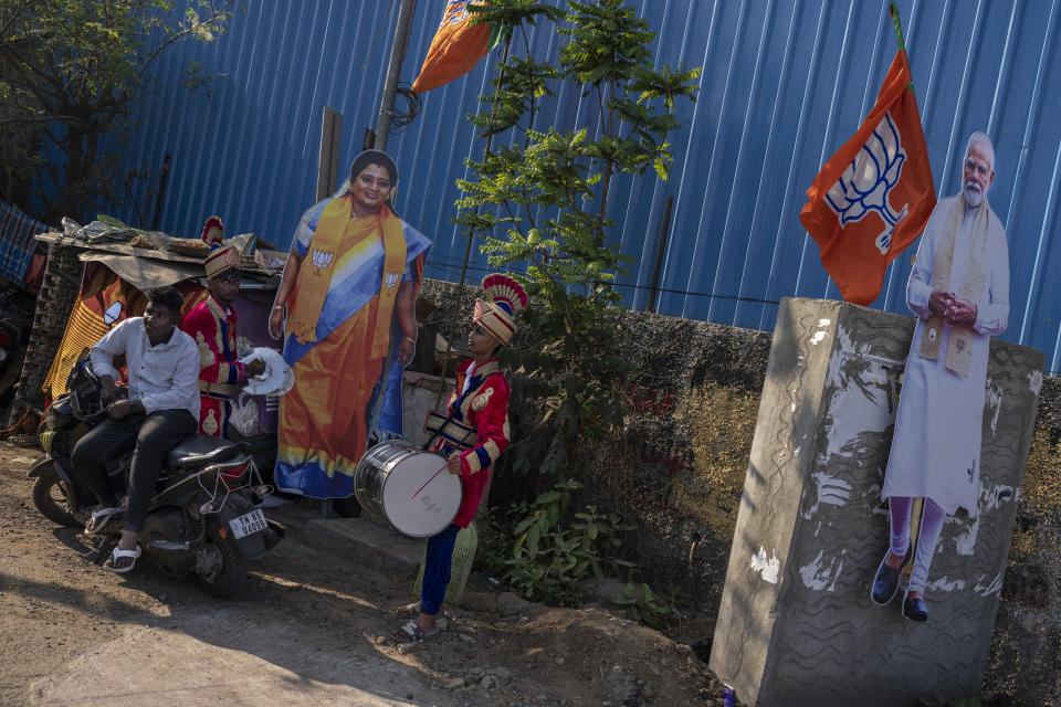 Members of a local band stand next to cutouts of Bharatiya Janata Party candidate Tamilisai Soundararajan and Prime Minister Narendra Modi, right, as they wait for her arrival for an election campaign rally, in the southern Indian city of Chennai, April 14, 2024. (AP Photo/Altaf Qadri)