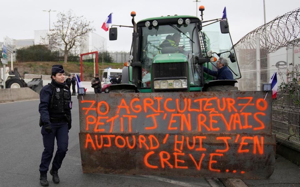 A police officer walks past a farmer outside the Rungis international market, Jan 31