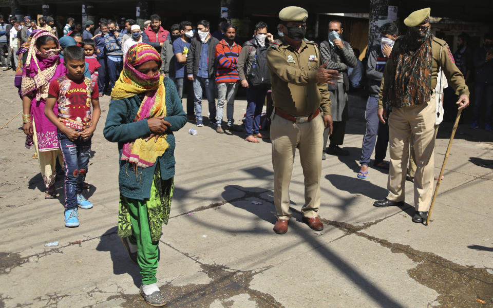 Indian passengers who got stranded at a bus terminal line up for free food being distributed by shop keepers during a day long lockdown amid growing concerns of coronavirus in Jammu, India, Sunday, March 22, 2020. India is observing a 14-hour “people's curfew” called by Prime Minister Narendra Modi in order to stem the rising coronavirus caseload in the country of 1.3 billion. For most people, the new coronavirus causes only mild or moderate symptoms. For some it can cause more severe illness. (AP Photo/Channi Anand)