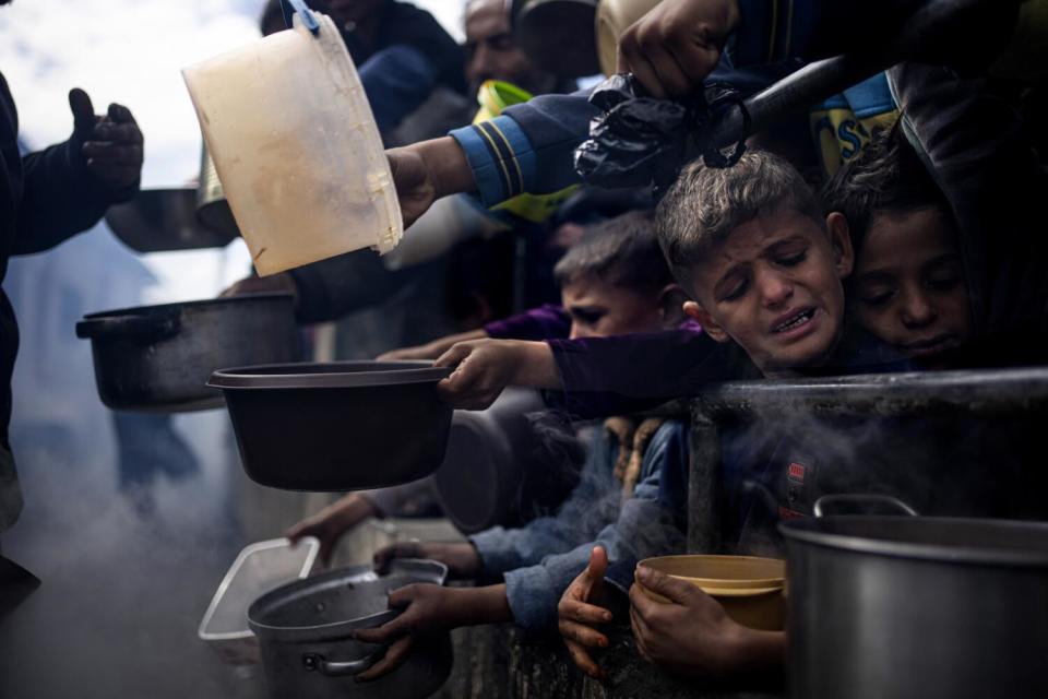 People cram together holding pots and other containers