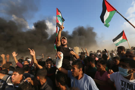 Palestinians shout slogans during a protest calling for lifting the Israeli blockade on Gaza and demanding the right to return to their homeland, at the Israel-Gaza border fence in the southern Gaza Strip October 12, 2018. REUTERS/Ibraheem Abu Mustafa