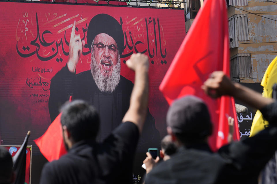 Hezbollah leader Sheik Hassan Nasrallah speaks via a video link, as his supporters raise their hands, during the Shiite holy day of Ashoura, in the southern suburb of Beirut, Lebanon, in Beirut, Lebanon, Tuesday, Aug. 9, 2022. The leader of Lebanon’s militant Hezbollah group has issued warning to archenemy Israel over the two countries' maritime border dispute. (AP Photo/Hussein Malla)