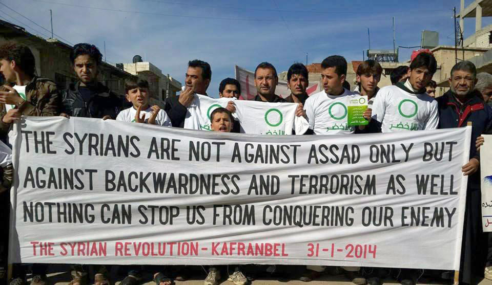 In this image provided by Edlib News Network (ENN), an anti-Bashar Assad activist group, which has been authenticated based on its contents and other AP reporting, anti-Syrian government protesters hold a banner during a demonstration at Kafr Nabil town in Idlib province, northern Syria, Friday, Jan. 31, 2014. (AP Photo/Edlib News Network ENN)
