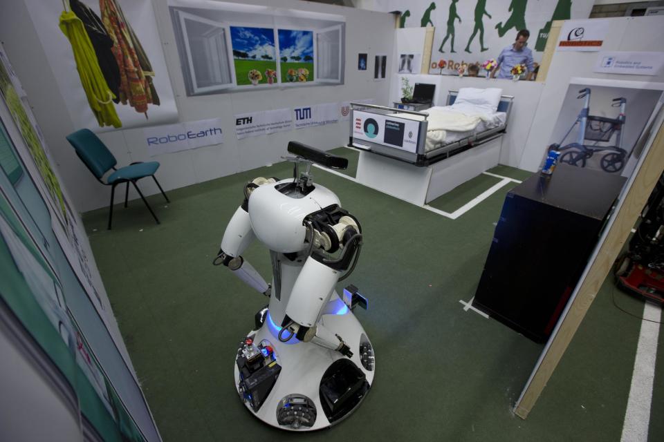 Amigo, a white robot the size of a person, uses information gathered by other robots to move towards a table to pick up a carton of milk and deliver it to an imaginary patient in a mock hospital room at the Technical University of Eindhoven, Netherlands, Wednesday Jan. 15, 2014. A group of five of Europe's top technical universities, together with technology conglomerate Royal Philips NV, are launching an open-source system dubbed "RoboEarth" Thursday. The heart of the mission is to accelerate the development of robots and robotic services via efficient communication with a network, or "cloud". (AP Photo/Peter Dejong)