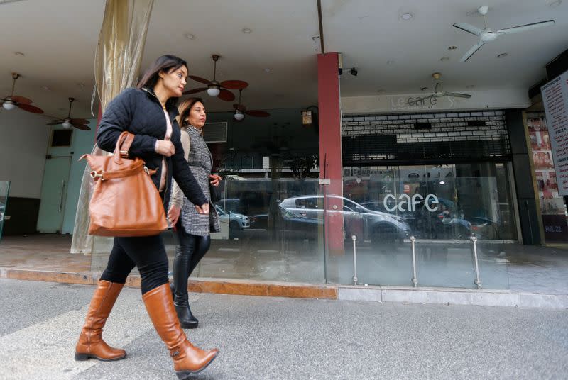 Women walk past a closed coffee shop in Beirut