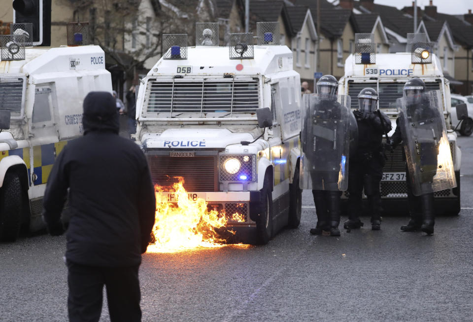 A Nationalist youth looks at a petrol bomb that was thrown at a police line blocking a road near the Peace Wall in West Belfast, Northern Ireland, Thursday, April 8, 2021. Authorities in Northern Ireland sought to restore calm Thursday after Protestant and Catholic youths in Belfast hurled bricks, fireworks and gasoline bombs at police and each other. It was the worst mayhem in a week of street violence in the region, where Britain's exit from the European Union has unsettled an uneasy political balance. (AP Photo/Peter Morrison)