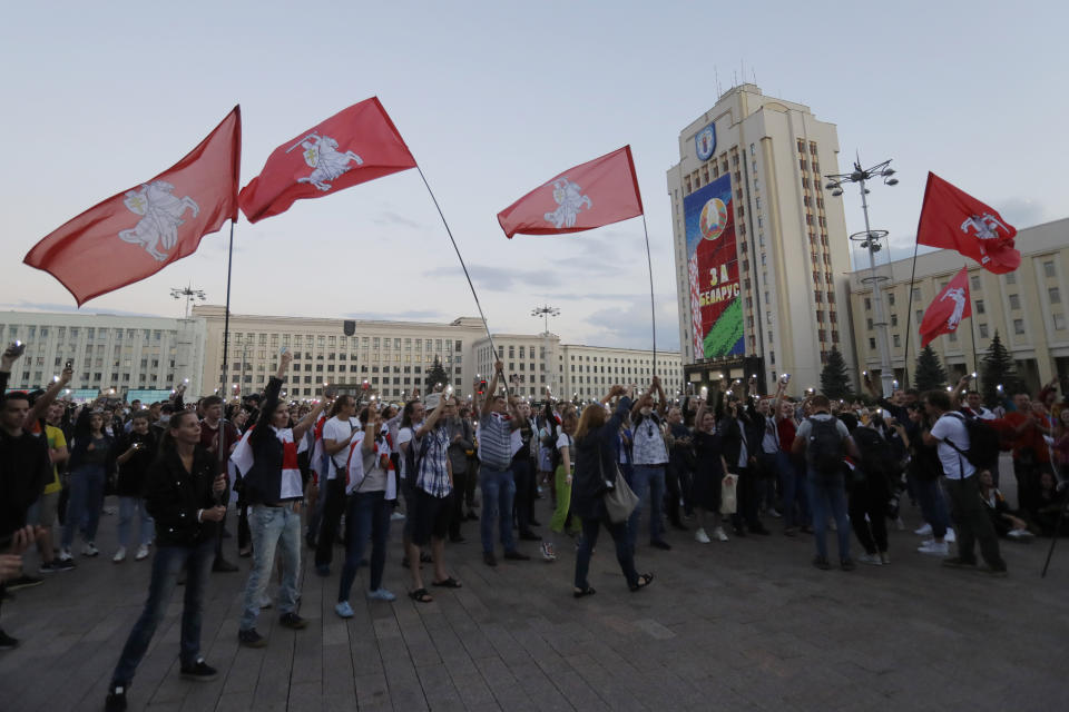 Protesters wave flags during an opposition rally at Independent Square in Minsk, Belarus, Monday, Aug. 24, 2020. Belarusian authorities on Monday detained three leading opposition activists who have helped spearhead a wave of protests demanding the resignation of the country's authoritarian president Alexander Lukashenko following a disputed election.(AP Photo/Sergei Grits)