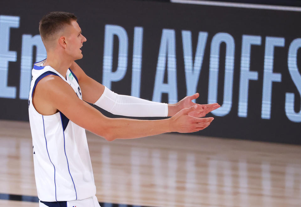 Dallas Mavericks center Kristaps Porzingis gestures with his hands outstretched in confusion.