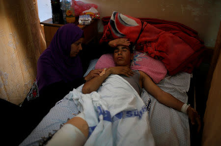 The mother of an injured Palestinian sits next to him as he lies on a bed at a hospital in Gaza City May 15, 2018. REUTERS/Mohammed Salem
