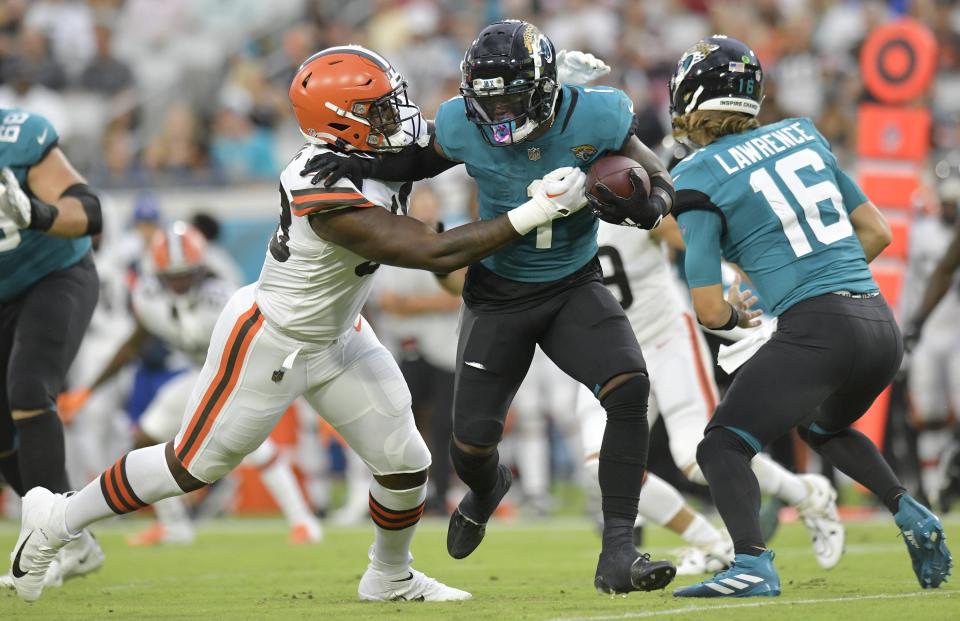 Jacksonville Jaguars running back Travis Etienne Jr. (1) tries to defend himself from Cleveland Browns defensive end Isaiah Thomas (58) on a handoff play during first quarter action. The Jacksonville Jaguars hosted the Cleveland Browns at TIAA Bank Field in Jacksonville, Florida Friday, August 12, 2022 for the first home preseason game of the season. [Bob Self/Florida Times-Union]