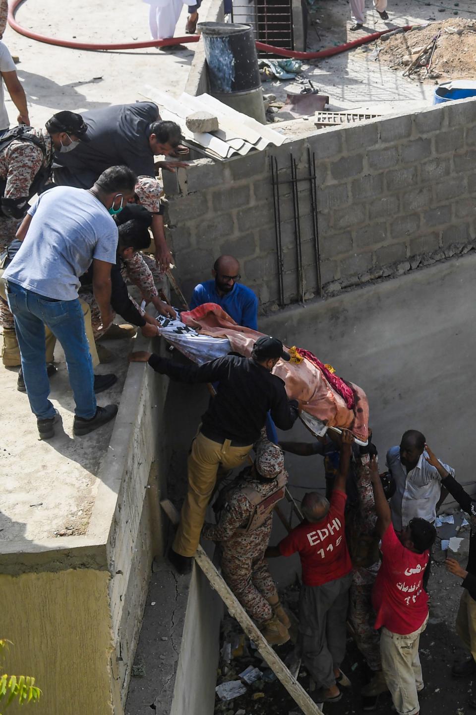 EDITORS NOTE: Graphic content / Rescue workers evacuate a body from the site after a Pakistan International Airlines aircraft crashed in a residential neighbourhood in Karachi on May 22, 2020. - A Pakistan passenger plane with more than 100 people believed to be on board crashed in the southern city of Karachi on May 22, the country's aviation authority said. (Photo by Asif HASSAN / AFP) (Photo by ASIF HASSAN/AFP via Getty Images)