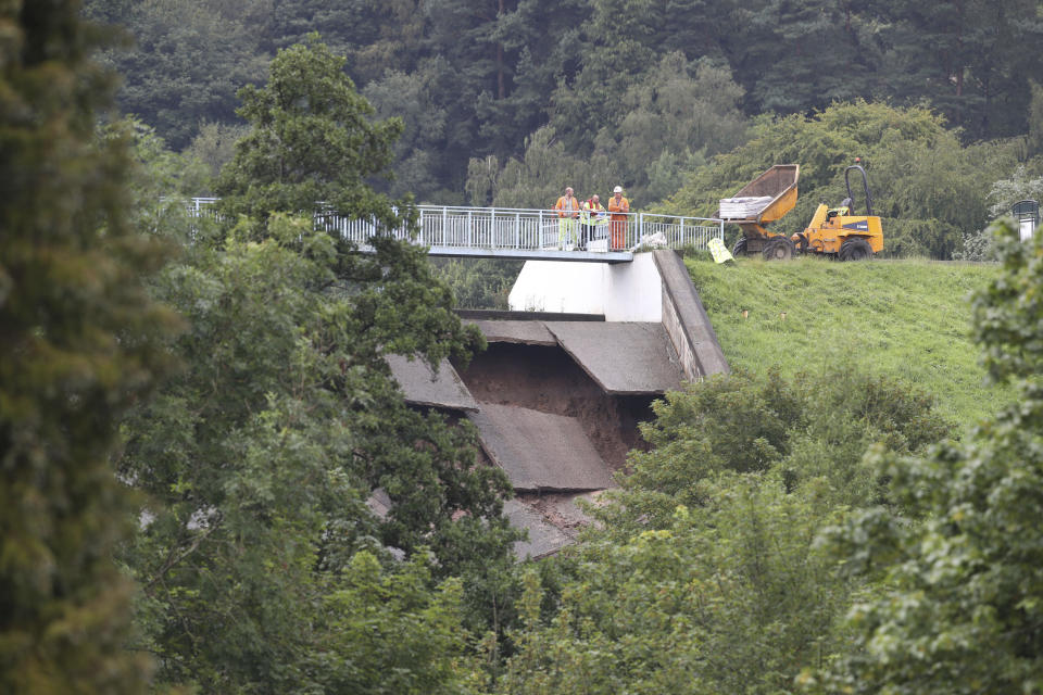 A team of men look at the damage to the wall of Toddbrook Reservoir near the village of Whaley Bridge, Cheshire, England, Thursday, Aug. 1, 2019. British police have ordered the evacuation of a town of 6,500 residents in northwest England over fears that a dam could collapse. The Derbyshire Police force says residents of Whaley Bridge should leave their homes because of the "significant threat to life." (Danny Lawson/PA via AP)